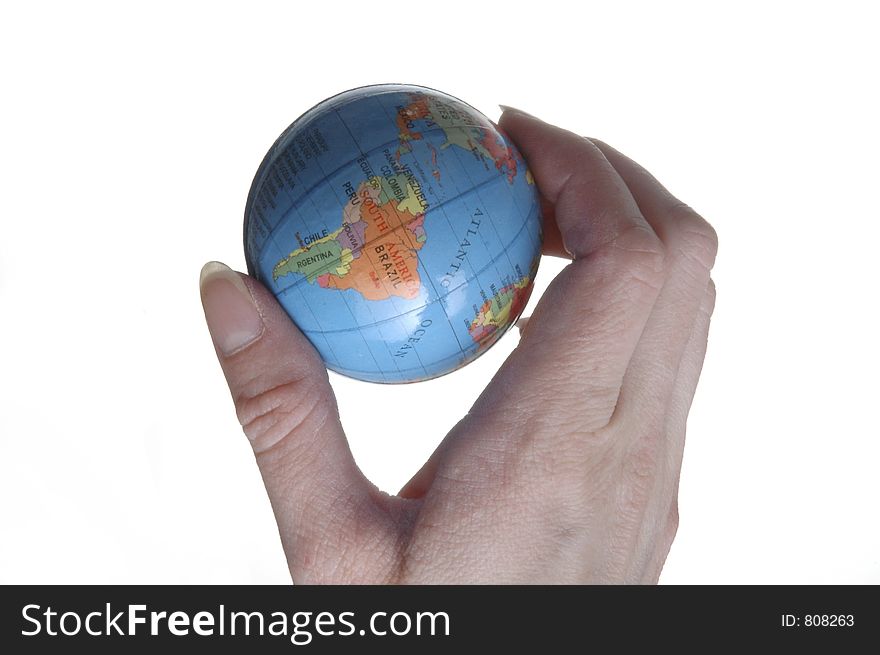 A hand holding a miniature globe. The western hemisphere is visible.