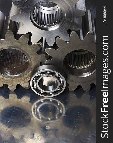 Three cogs, gears and ball-bearing, reflecting in stainless-steel. Three cogs, gears and ball-bearing, reflecting in stainless-steel