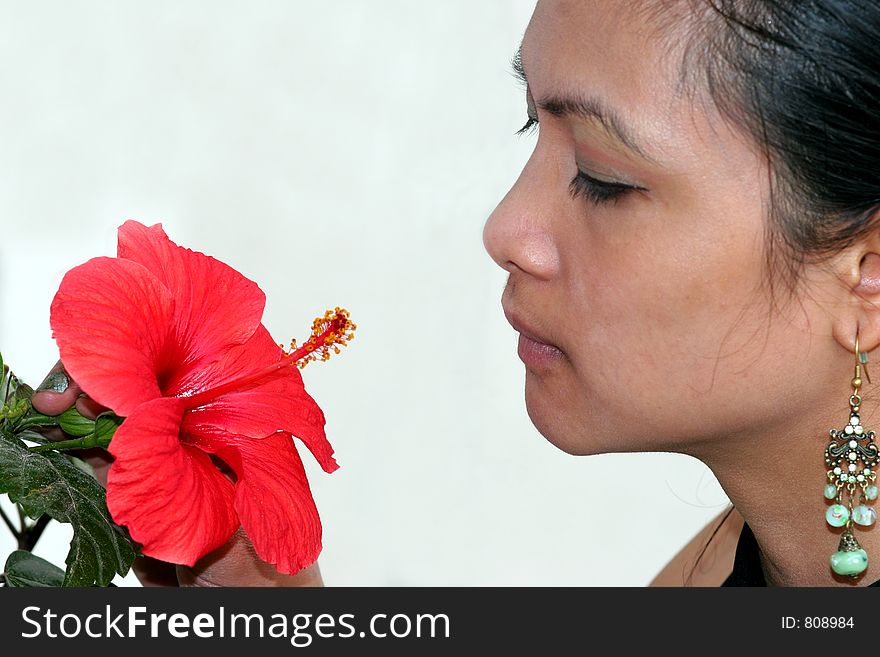 A young asian girl looking at the red flower. A young asian girl looking at the red flower