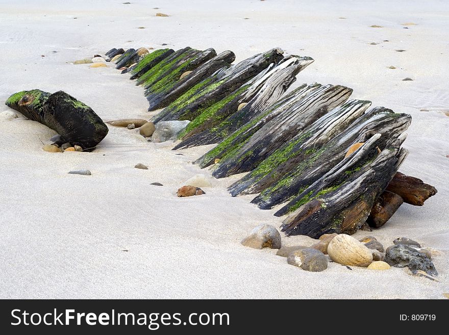 Remains of old wooden fishing boat buried in sand and pebbles. Remains of old wooden fishing boat buried in sand and pebbles.