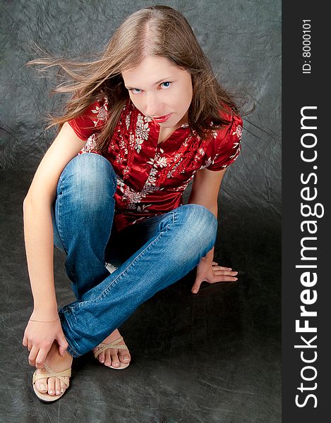 Pretty girl sitting on floor with legs crossed and looking up isolated on black background. Pretty girl sitting on floor with legs crossed and looking up isolated on black background