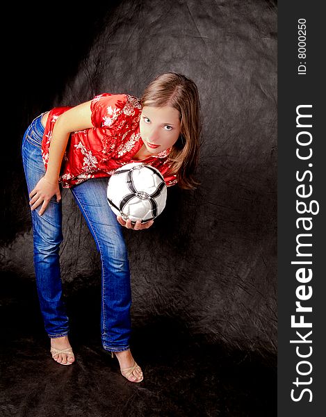 Young girl standing shaped with ball looking forward with hands supported hip isolated on black background