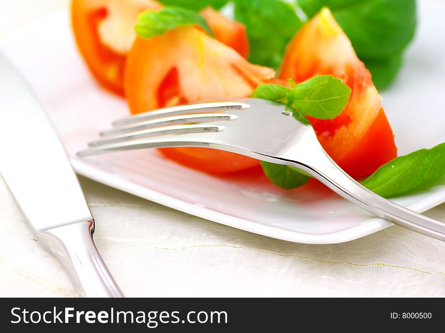 Fresh tomatoes with basil on a plate. Fresh tomatoes with basil on a plate