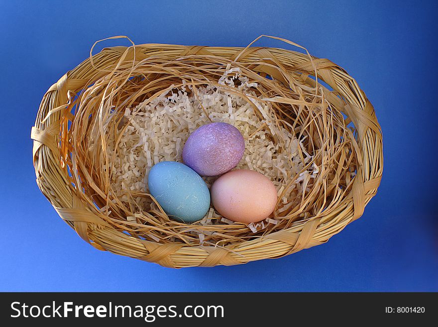 Easter eggs in wicker basket on blue background