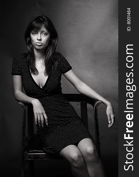 Black and white portrait of an attractive young woman sitting on a chair. Black and white portrait of an attractive young woman sitting on a chair