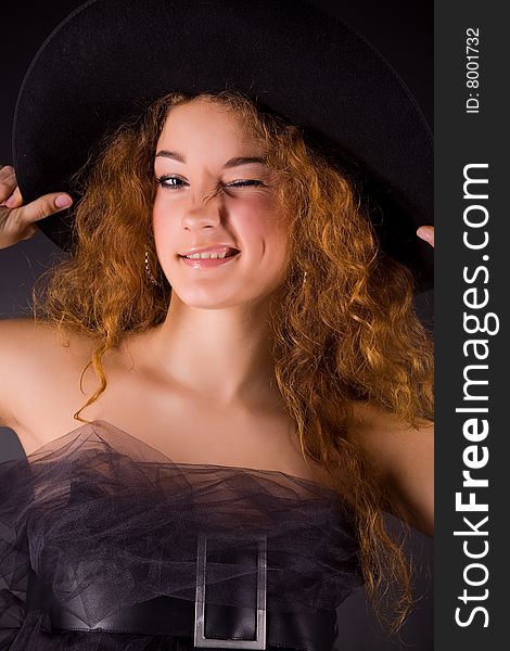 Winking red-haired girl in hat, studio shot