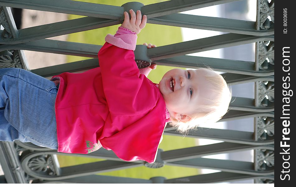 Little girl near the grate of bridge