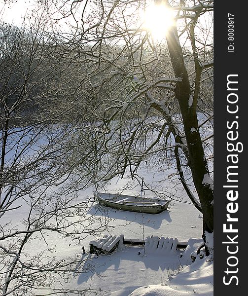 The winter sun casts its beams on the boat and the ramshackled bridge. The winter sun casts its beams on the boat and the ramshackled bridge