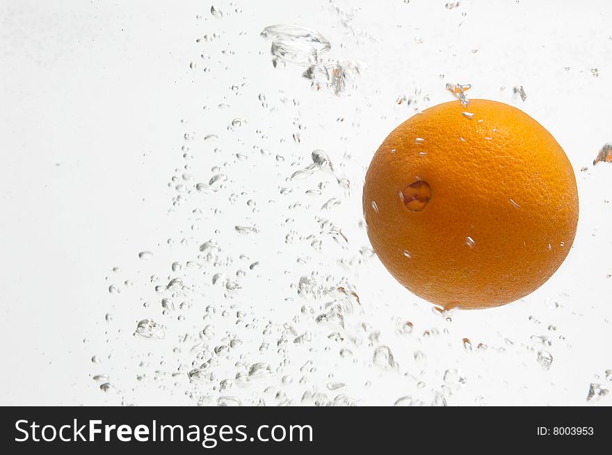 Fresh and juicy orange is dropped into water. Fresh and juicy orange is dropped into water.