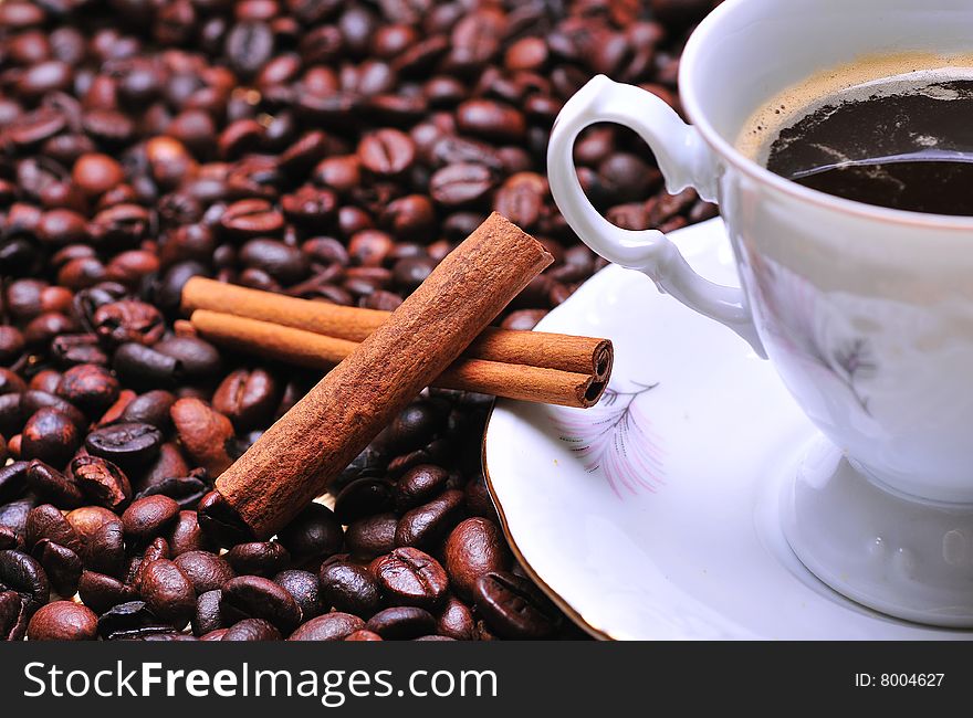A cup of coffee with cinnamon on beans. A cup of coffee with cinnamon on beans