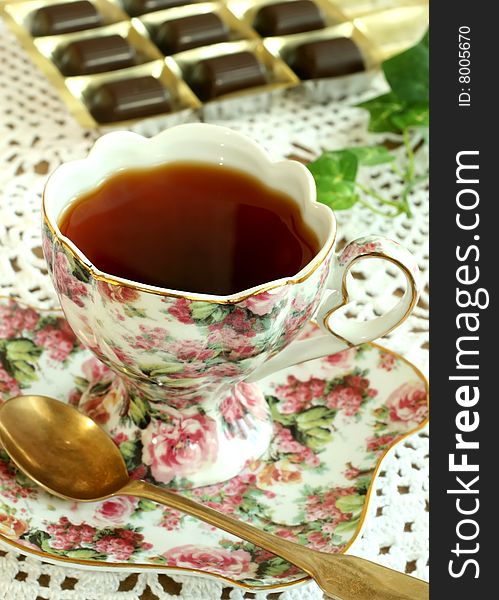 Cup of tea and chocolates on knitted table cover, closeup