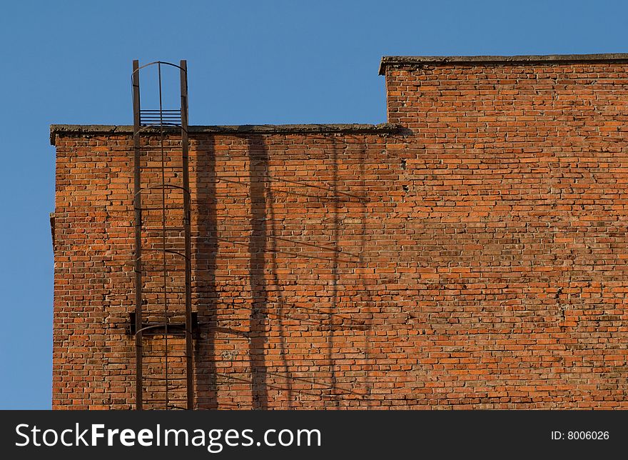 The metal staircase on the brick wall of building. The metal staircase on the brick wall of building