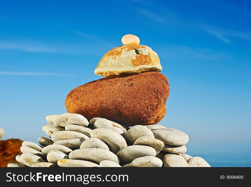 The big red stone at top of a pyramid at the sea in the summer. The big red stone at top of a pyramid at the sea in the summer