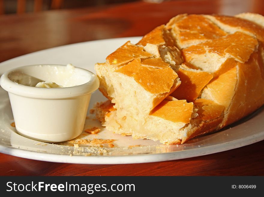 A plate of fresh butter and a crusty loaf of bread warm from the oven. A plate of fresh butter and a crusty loaf of bread warm from the oven.