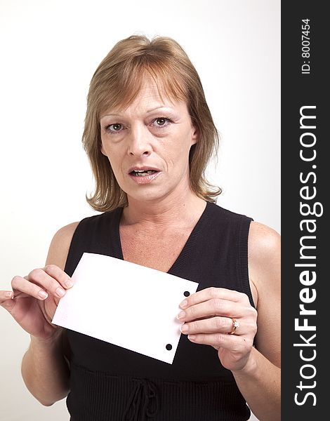A mature business woman showing surprise while holding up a blank pink slip of paper. A mature business woman showing surprise while holding up a blank pink slip of paper