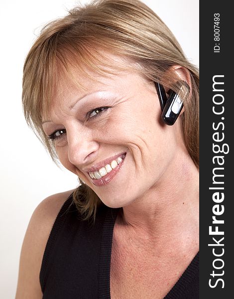 A beautiful mature woman with a wireless earpiece and head tilted to side. A beautiful mature woman with a wireless earpiece and head tilted to side