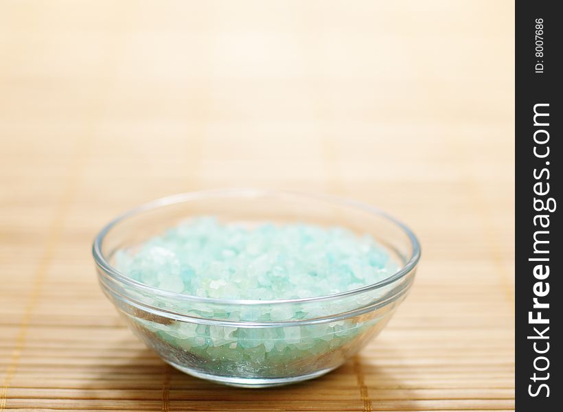 Colored bath salt displayed on top of a bamboo mat.