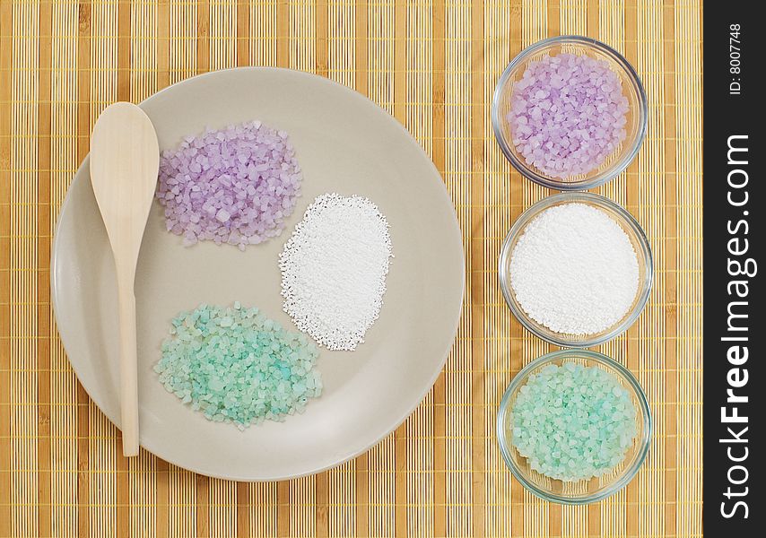 Colorful bath salts on display against a bamboo mat. Colorful bath salts on display against a bamboo mat.