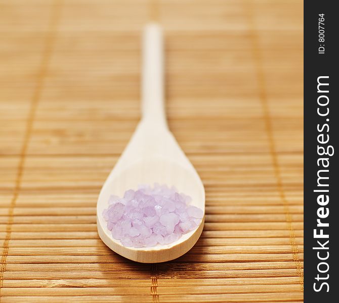 Bath salt and wooden spoon on display against bamboo mat. Bath salt and wooden spoon on display against bamboo mat.