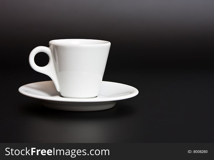 White coffee cup and saucer on a black background. White coffee cup and saucer on a black background.
