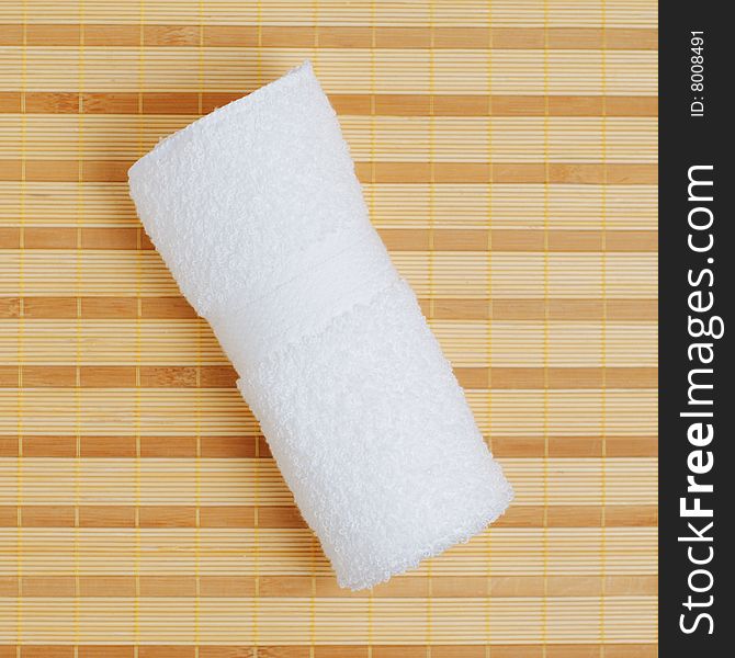 White towel against bamboo reed mat background. White towel against bamboo reed mat background.