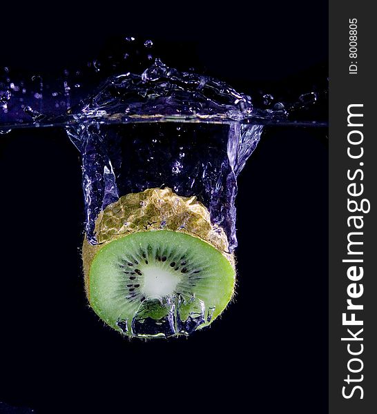 Kiwi  in water with bubbles on black ground. Kiwi  in water with bubbles on black ground