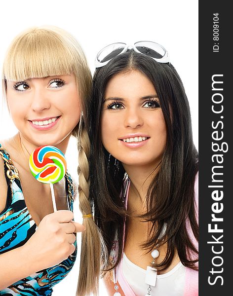 Portrait of two beautiful happy girls with a lollipop against white background