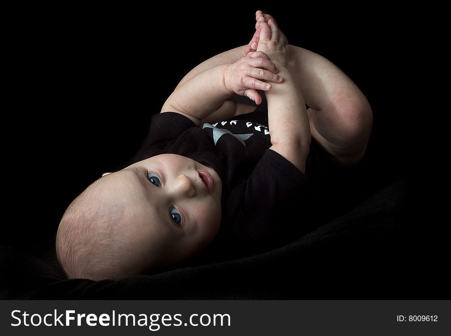 Happy little baby girl with blue eyes isolated on black