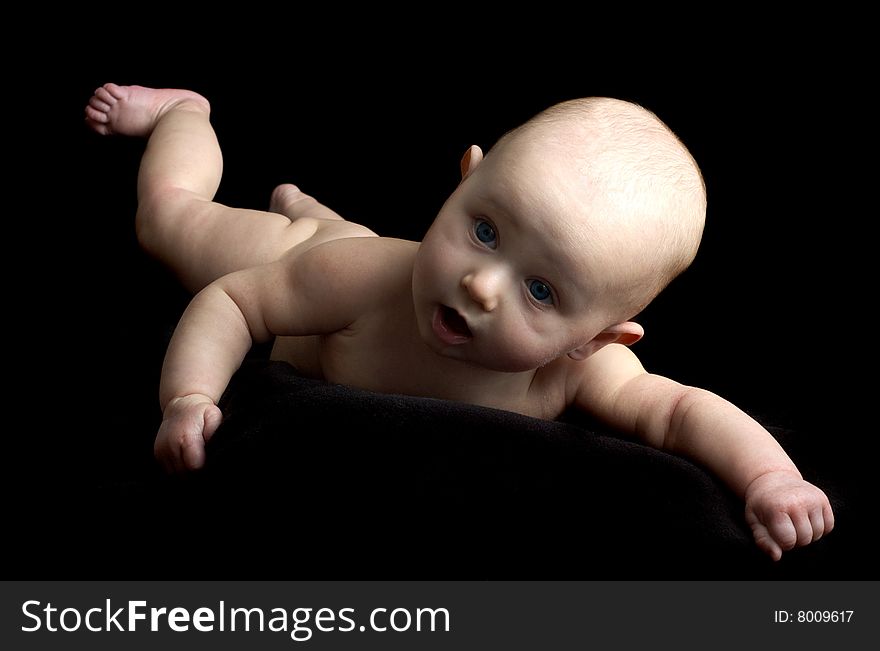 Happy little baby girl with blue eyes isolated on black