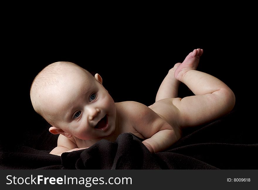 Happy little baby girl with blue eyes isolated on black