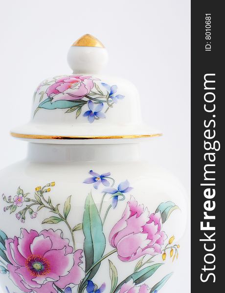 Oriental ginger jar with a floural motiff.  Roses and other colorful flowers adorn the front of the jar, the lid has a gold top and a gold rim.