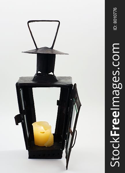 Old candlestick lantern made with metal construction and glass on four sides with a lit candle inside. Old candlestick lantern made with metal construction and glass on four sides with a lit candle inside.