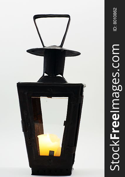 Old candlestick lantern made with metal construction and glass on four sides with a lit candle inside. Old candlestick lantern made with metal construction and glass on four sides with a lit candle inside.