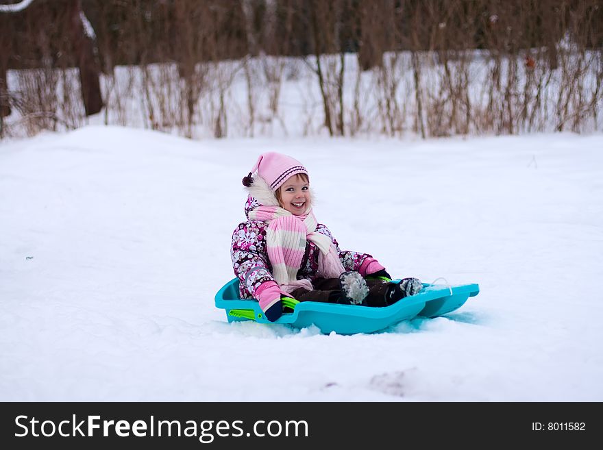 Smileing little girl on sleigh. She laughting.