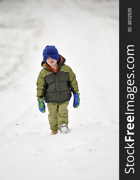 A little boy walks down a path in the snow. A little boy walks down a path in the snow