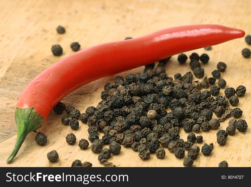 Close-up of black and red pepper lying on wooden background. Close-up of black and red pepper lying on wooden background