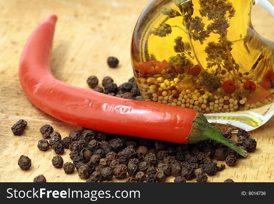 Nice bottle of olive oil and various pepper on wooden background. Nice bottle of olive oil and various pepper on wooden background