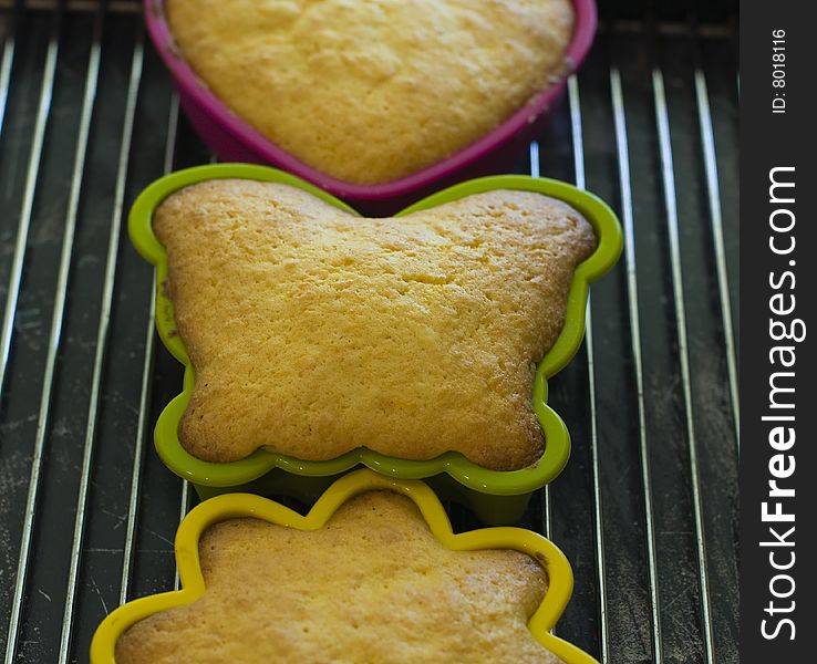 Mini cakes in coloured silicone moulds baking in the oven. Mini cakes in coloured silicone moulds baking in the oven