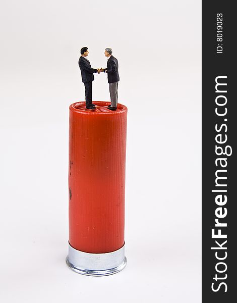 Miniature businessmen shaking hands on a shotgun round. Miniature businessmen shaking hands on a shotgun round.