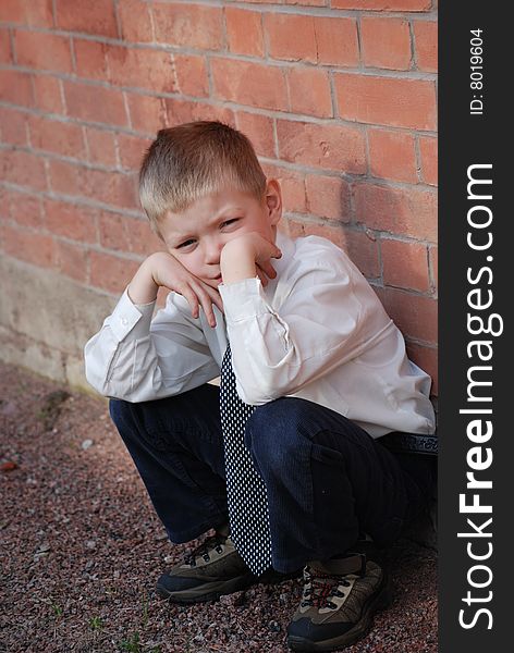 a boy squatting on hams on a background a brick wall, propping up hands person