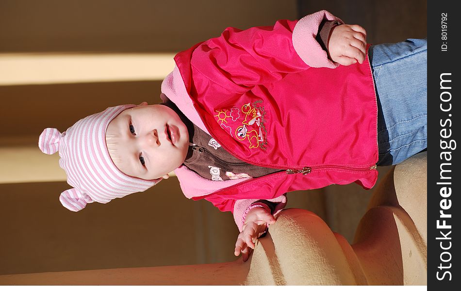 Little girl in a brightly red jacket near a column. Little girl in a brightly red jacket near a column