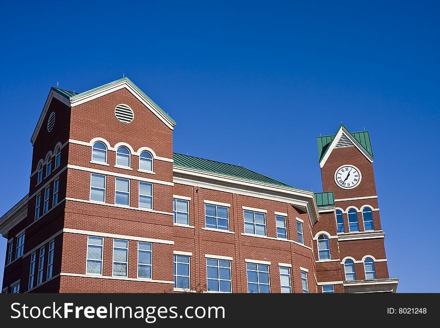 A brick courthouse with a clock against a blue sky. A brick courthouse with a clock against a blue sky