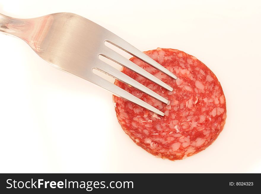 Piece of the sausage on the fork under the white background