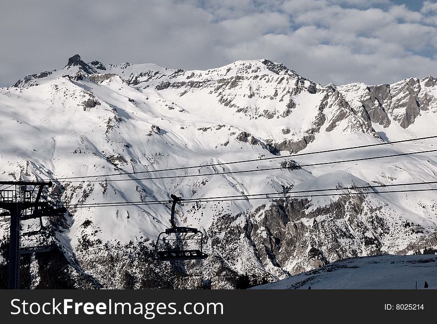 An empty ski lift against the background of mountain peaks covered in sno. An empty ski lift against the background of mountain peaks covered in sno