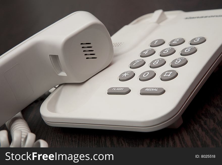 White office phone with a receiver on hold. White office phone with a receiver on hold