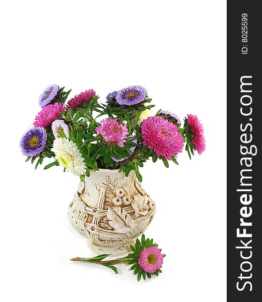 The bouquet from small asters costs in a clay vase. The vase is isolated on a white background