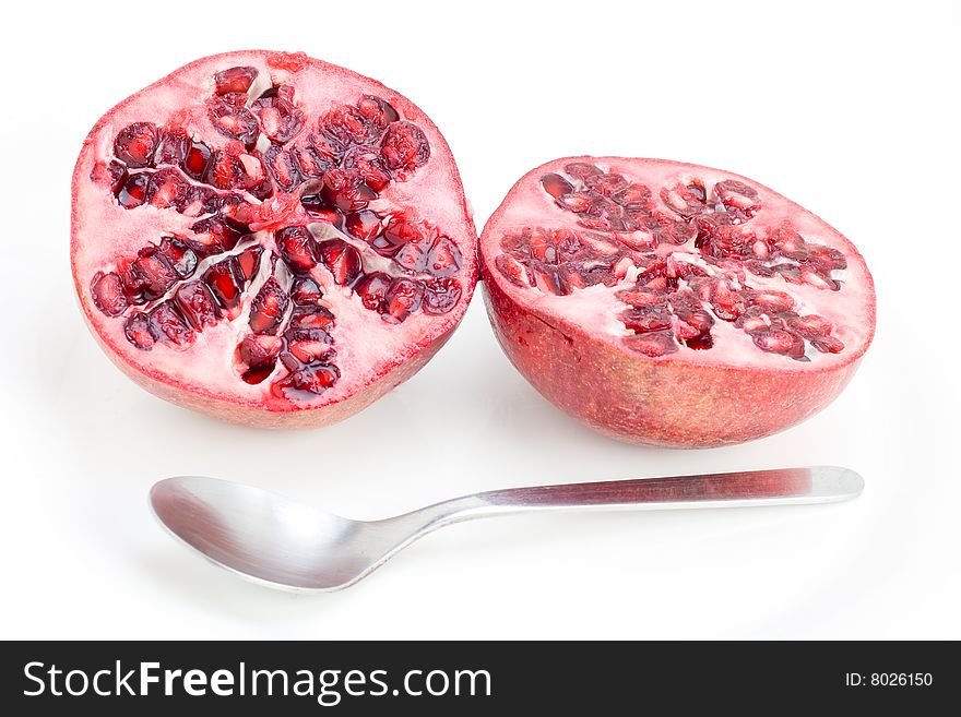 A fresh halved Pomegranate with spoon isolated on white. A fresh halved Pomegranate with spoon isolated on white