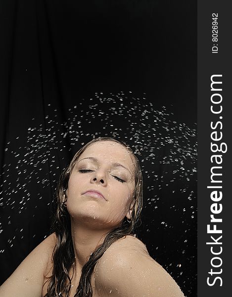 Portrait of woman taking a shower on black background