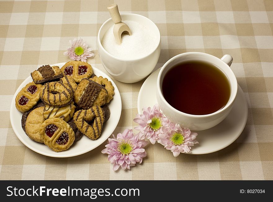 An afternoon tea theme with biscuits, cake, sugar and flowers in beige and pink - cozy still life. An afternoon tea theme with biscuits, cake, sugar and flowers in beige and pink - cozy still life.