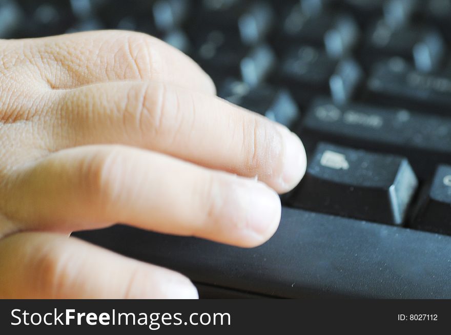 The child's hand and fingers on the computer keys.